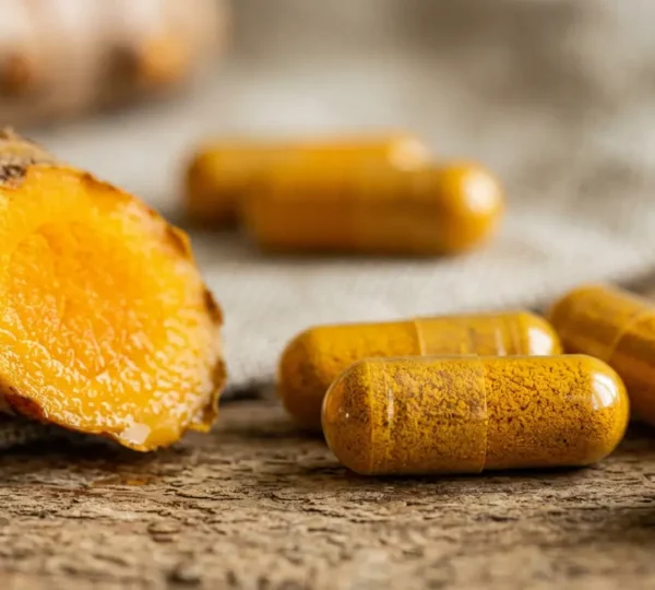 Gélules de curcuma dorées et rhizome frais symbolisant le soulagement naturel des articulations