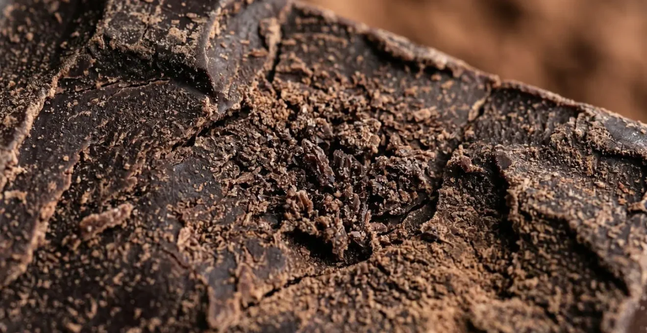 Gros plan sur la texture d'une tablette de chocolat noir 85%, mettant en évidence sa composition pure et de qualité.