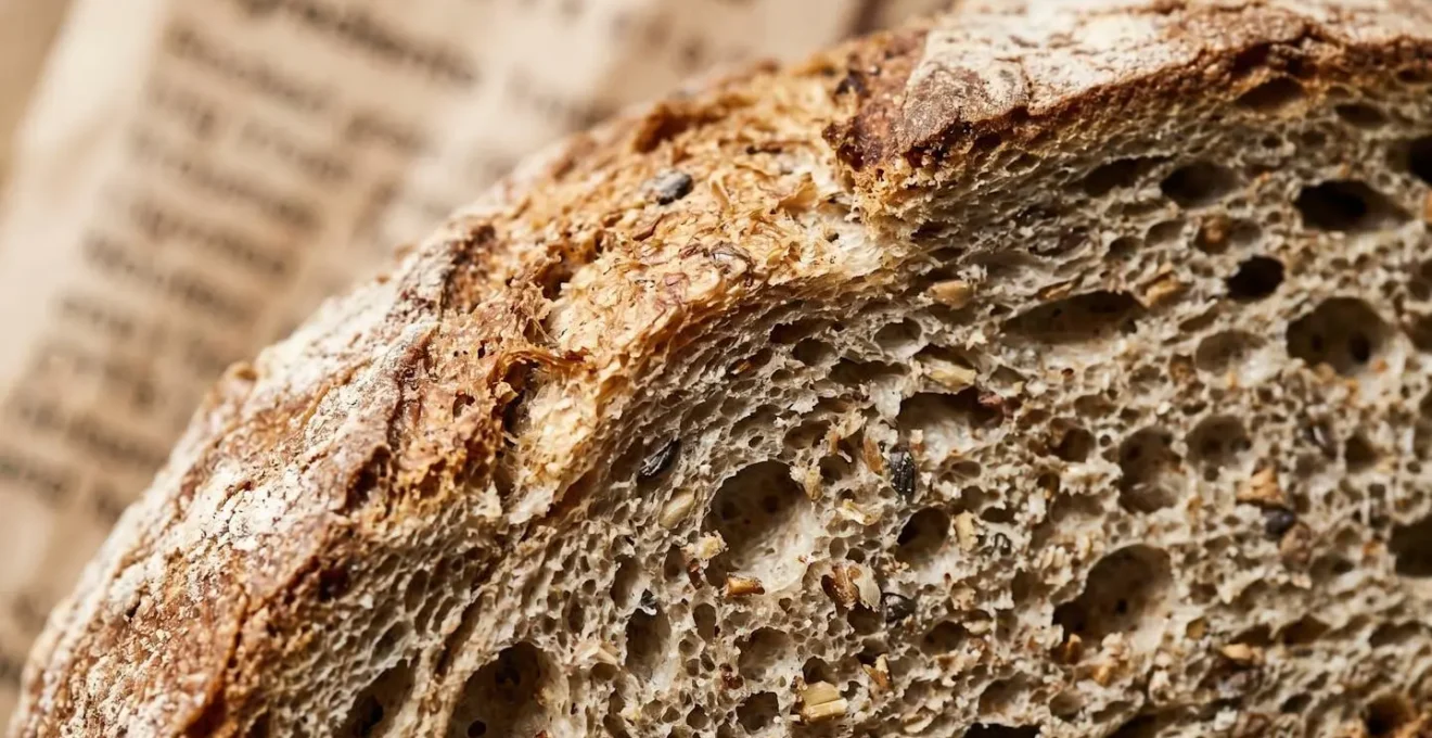 Gros plan macro sur une liste d'ingrédients floue d'un pain, avec focus sur les textures de la mie et de la croûte en arrière-plan