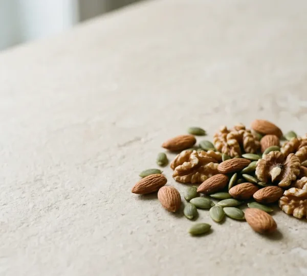 Poignée d'amandes, noix et graines de courge sur fond naturel minimaliste illustrant les sources d'oléagineux riches en magnésium et zinc